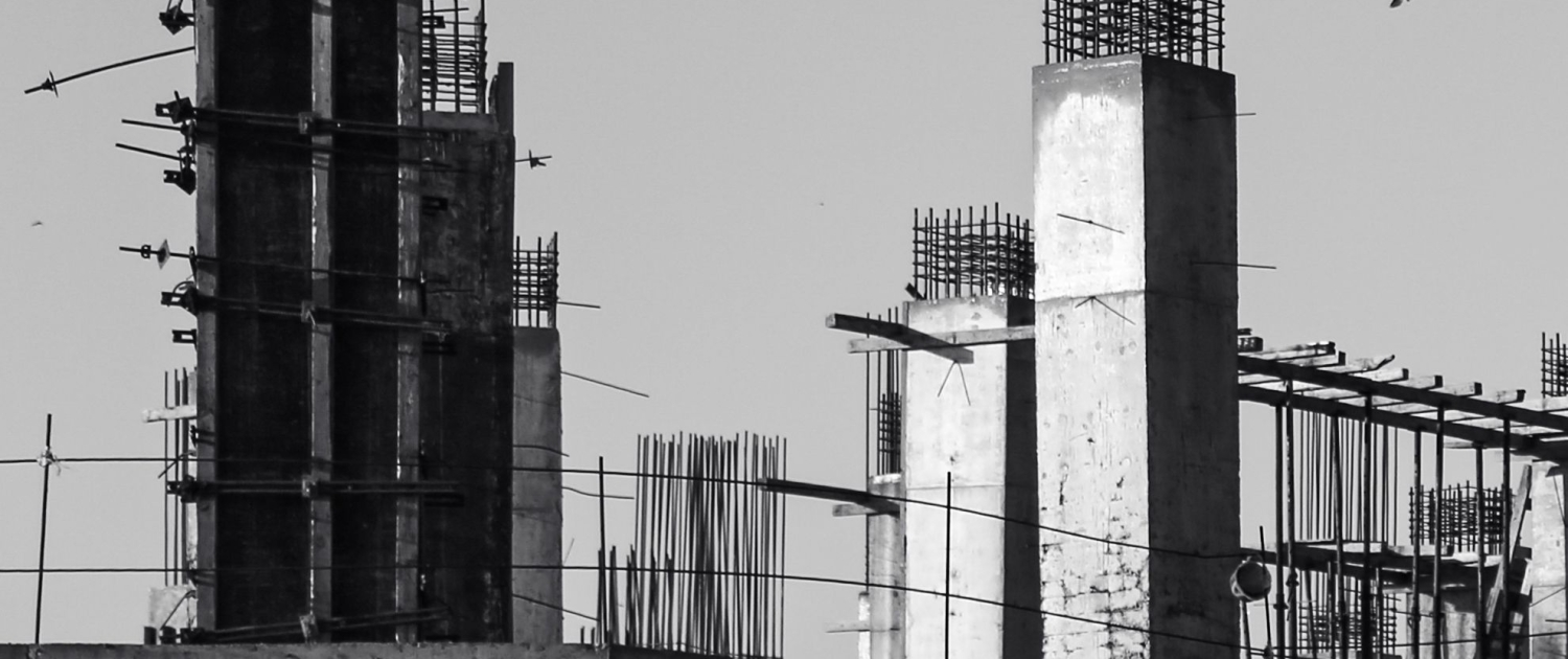 Pilares y vigas de hormigón de un edificio en construcción, fotografiados en blanco y negro.