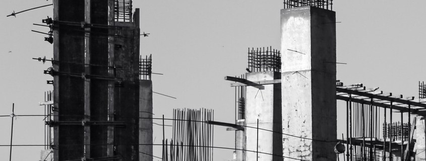 Pilares y vigas de hormigón de un edificio en construcción, fotografiados en blanco y negro.